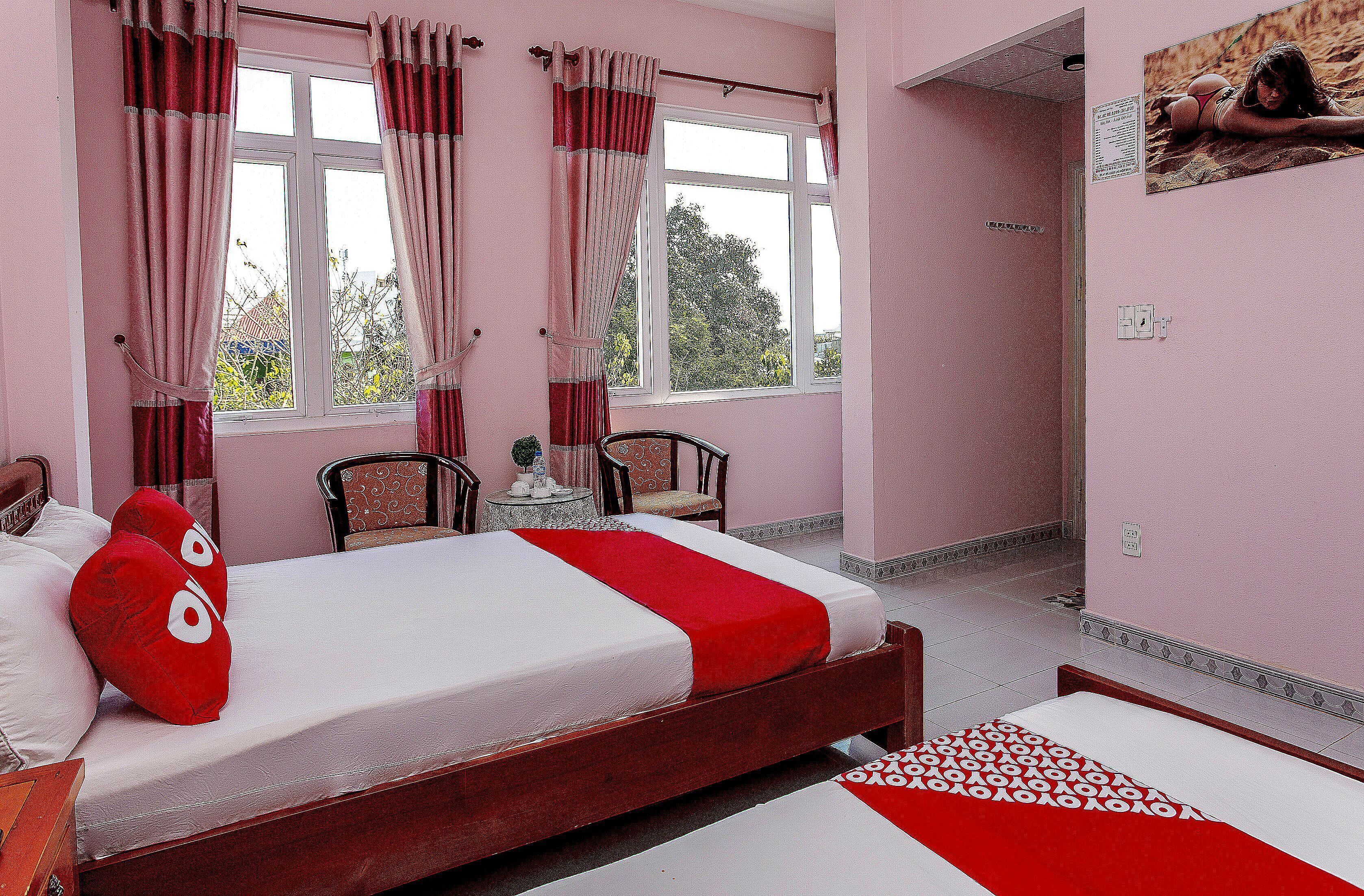 A room with a bed, a chair, a small table, and a window with curtains.