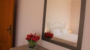Une chambre à coucher avec un lit, une table de chevet et un miroir qui reflète la pièce.