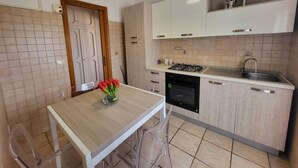 Une cuisine moderne avec une table en bois, un four encastré et des armoires blanches.