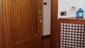 Une porte en bois portant le numéro 2, un petit thermostat numérique et un jouet en peluche bleu sur une table en bois.