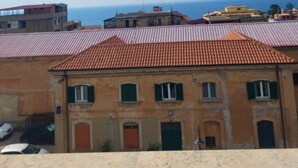 Un bâtiment situé sur la côte, avec un toit recouvert de tuiles rouges, un balcon et une vue sur la mer.