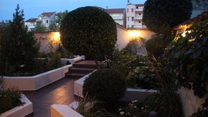 En innergård med en stenlagd gång, en liten sittplats och välklippta buskar.