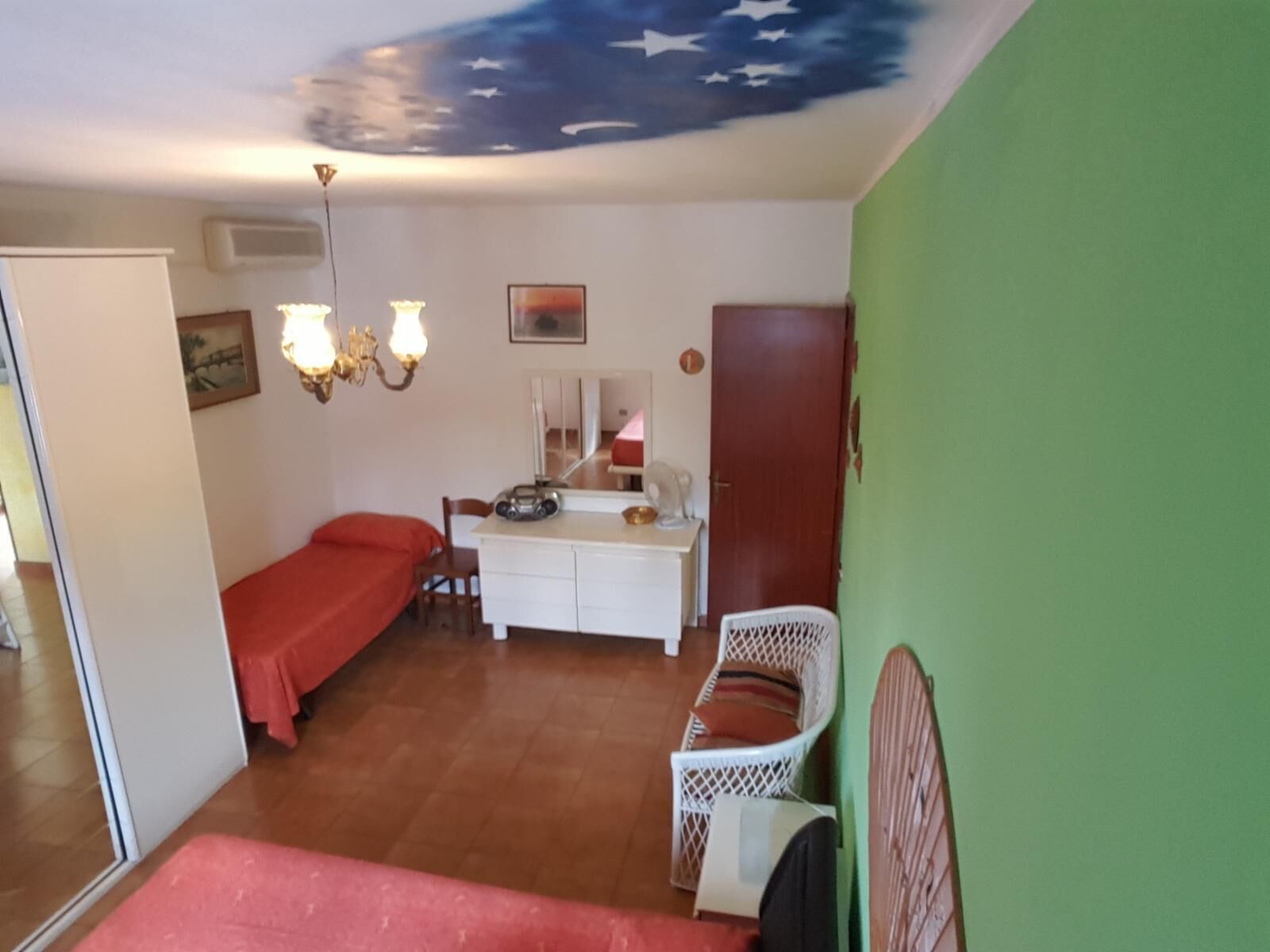 A room with a bed, a desk with a chair, a mirror, and a wall with a star design.