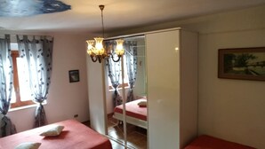 Un dormitorio con dos camas, un armario, una araña y un cuadro en la pared.