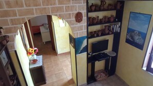 Una habitación con pared de ladrillo, estante con cerámica, televisor y un cuadro en la pared.