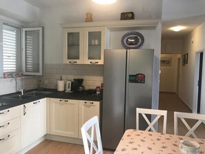 Een keuken met witte kasten, een roestvrijstalen koelkast en een eettafel met stoelen.