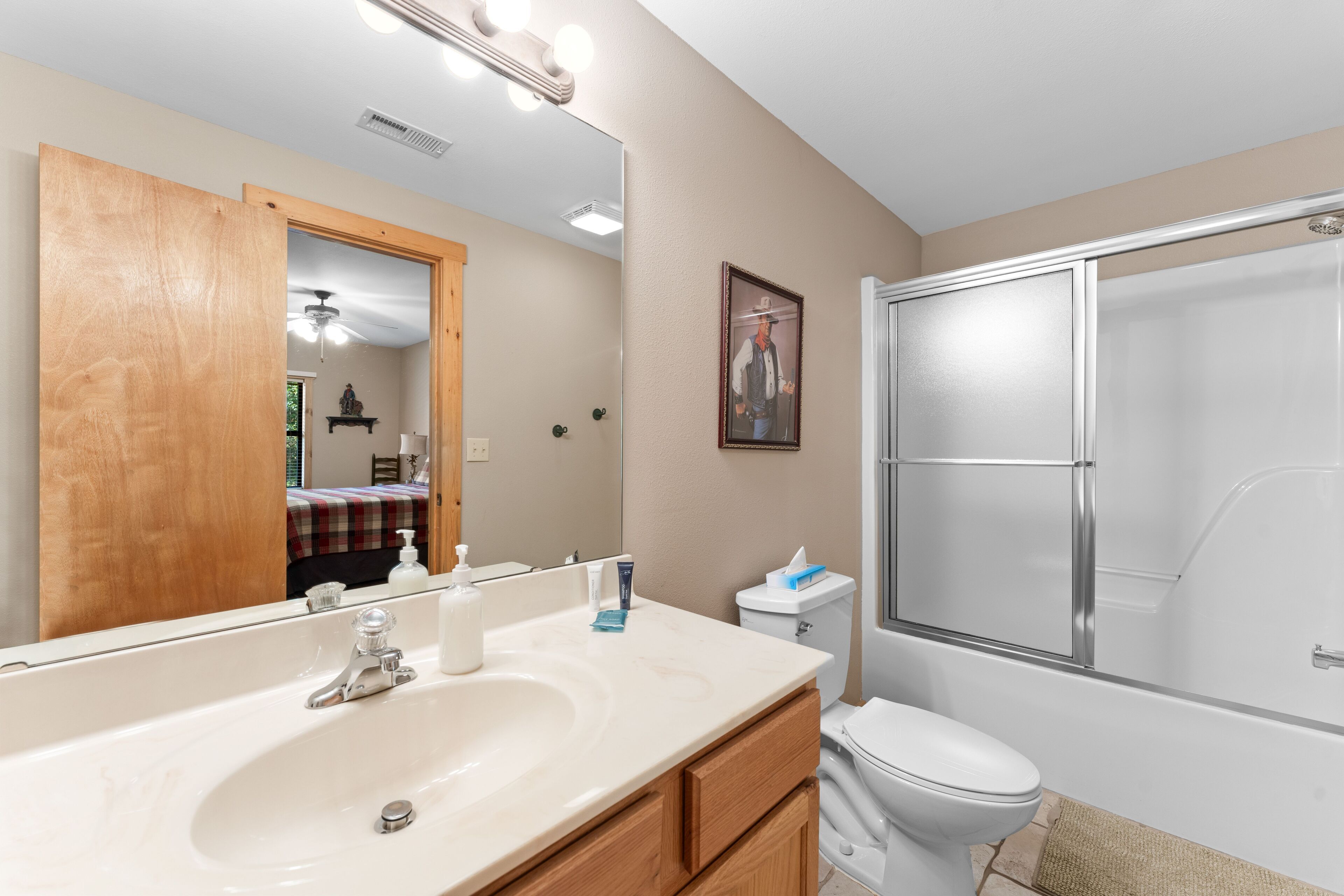 A bathroom with a large mirror, a sink, a toilet, and a shower.