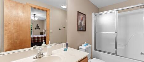 A bathroom with a large mirror, a sink, a toilet, and a shower.