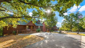 A row of log cabins with a paved driveway and surrounding trees. - Ozarks Oasis 4 Bedroom Cabin by RedAwning (Branson)