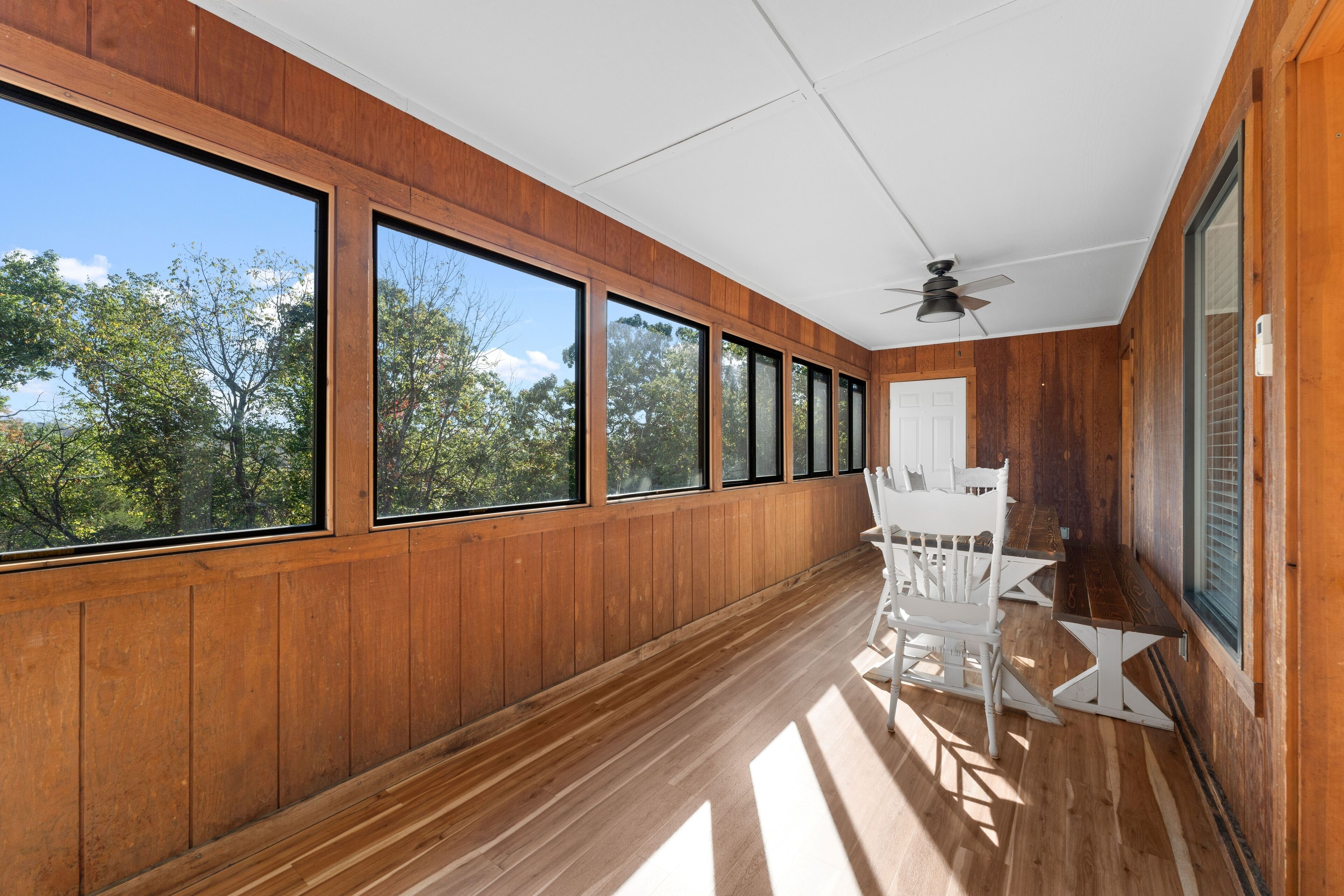 Una stanza ampia con ampie finestre, pareti in legno e una ventola a soffitto.