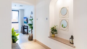A modern hotel lobby with a clean, minimalist design, featuring a flat-screen TV, potted plants, and a small table with a lamp. - Maison Privee - Luxury Living Next to Dubai Mall & Burj Khalifa (Dubai)