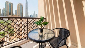 A balcony with a round glass table and two chairs, a potted plant, and a view of the Dubai skyline including the Burj Khalifa. - Maison Privee - Luxury Living Next to Dubai Mall & Burj Khalifa (Dubai)