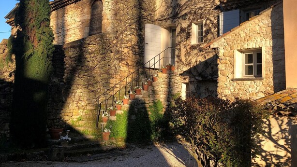 Un bâtiment en pierre doté d’une cour, d’un escalier et d’un petit jardin.