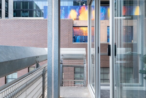 A building with a glass door, a metal railing, and a brick wall.