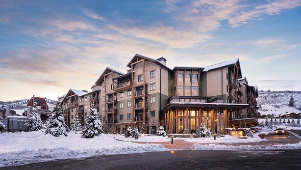 A multi-story hotel with a ski resort backdrop, featuring a prominent entrance and a snow-covered landscape.
