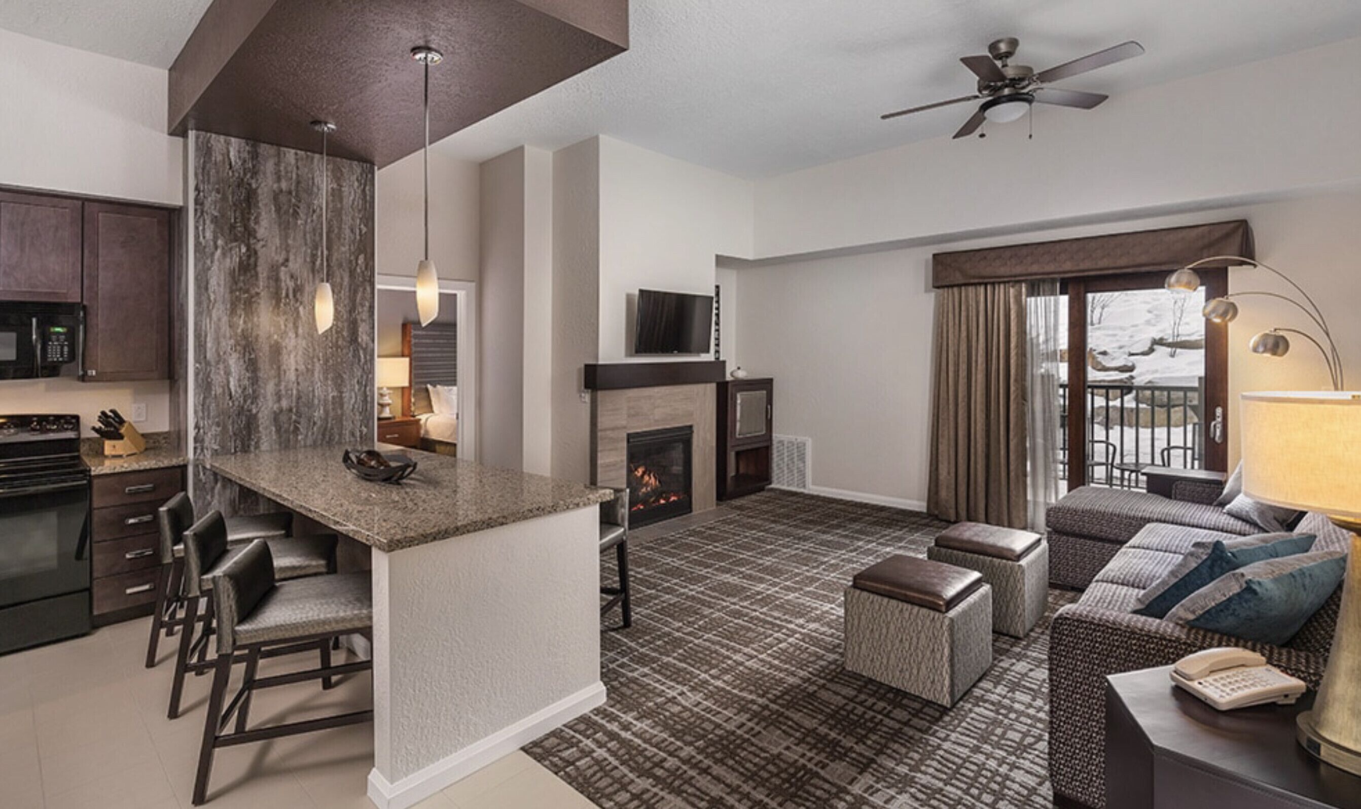 A modern living room with a fireplace, a TV, and a balcony with a view.
