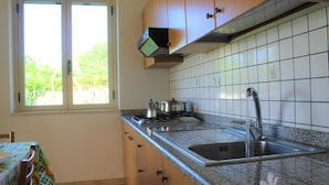 Una cocina con gabinetes de madera, encimera de granito, estufa y pileta.