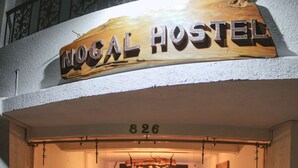 A wooden sign with "NOGAL HOSTEL" and a number "826" above a reception desk. - Nogal Hostel (Pereira)