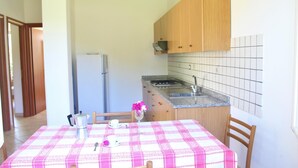 A kitchen with wooden cabinets, a granite countertop, and a tiled backsplash. - Villa Faro with panoramic garden and barbecue. 350m from the sea (RICADI)