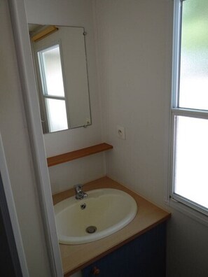 A bathroom with a white sink, a mirror, and a window.