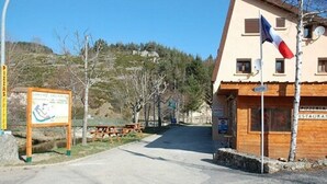 A building with a signboard, a flag, and a restaurant sign. - Camping Les Airelles (Saint-Cirgues-en-Montagne)
