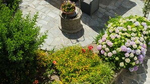 Eine Terrasse im Freien mit Tisch und Stühlen, umgeben von verschiedenen Pflanzen und Blumen.