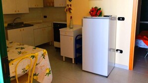 Une cuisine compacte équipée d’un réfrigérateur, d’un évier et d’un coin repas avec une table et des chaises.