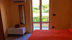 Une chambre à coucher comprenant un lit, une commode, un miroir et une porte donnant sur un balcon.