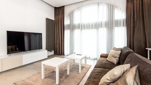 Een moderne woonkamer met een flatscreen televisie, een witte salontafel en een bruine bank.