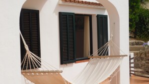 Un edificio blanco con dos ventanas y una hamaca.