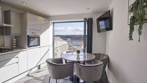 A modern kitchen with a dining area, large windows, and a flat-screen TV. - Host & Stay | The View, Hudsons Yard House (Whitby)