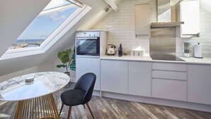 A modern kitchen with a skylight, white cabinetry, and a view of the sea. - Host & Stay | The Penthouse, Hudsons Yard House (Whitby)