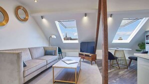A modern loft apartment with a high ceiling, skylights, a sofa, a coffee table, a TV, and a dining area. - Host & Stay | The Penthouse, Hudsons Yard House (Whitby)