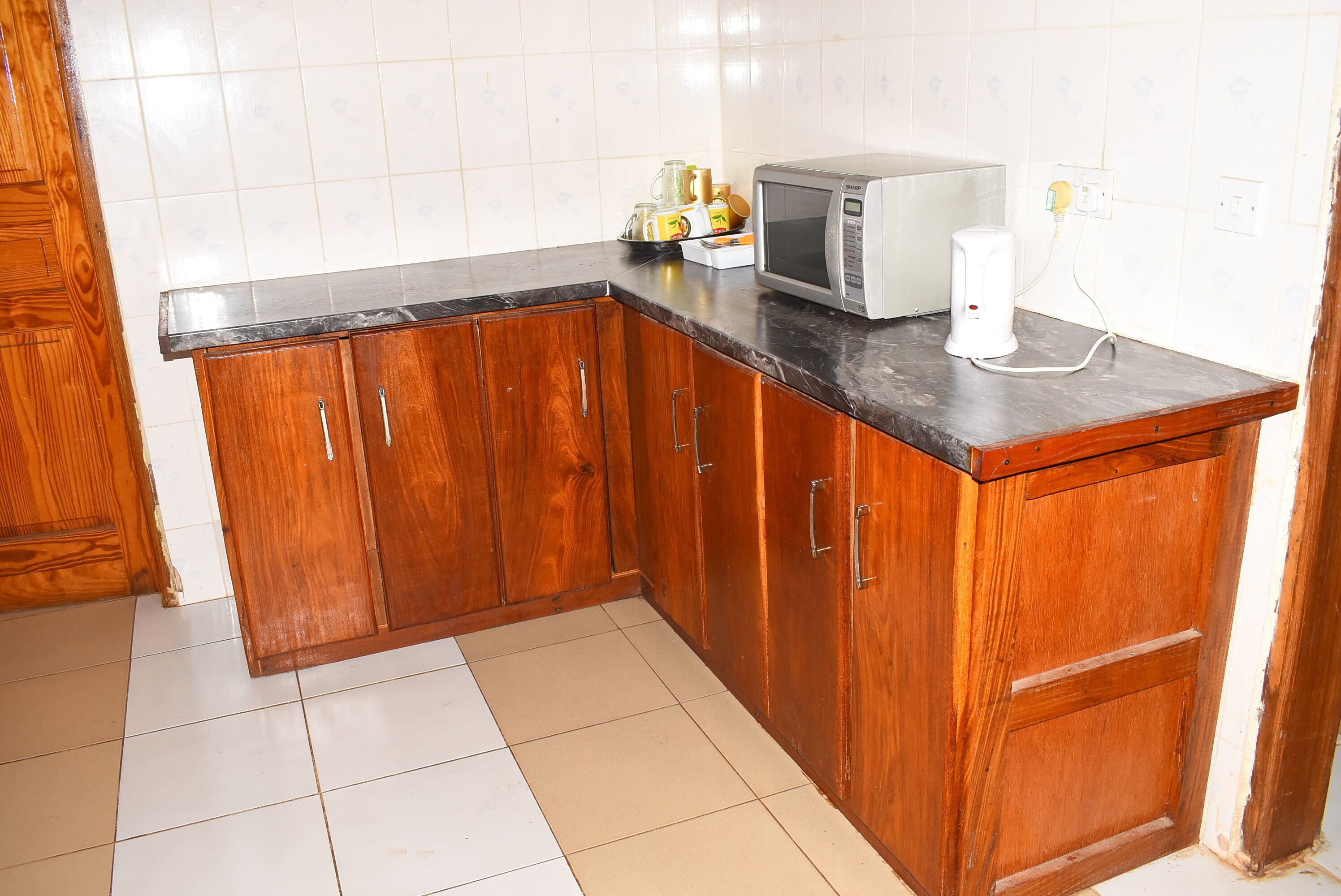 A kitchen with wooden cabinets, a microwave, and a kettle on the countertop.