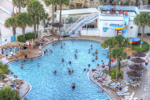 A large indoor swimming pool with multiple lanes, surrounded by palm trees and sun loungers.