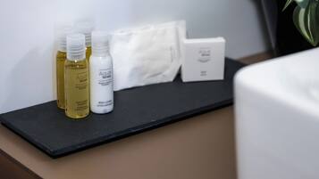 A bathroom counter with toiletries including shampoo, body lotion, and a box.