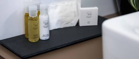 Un meuble-lavabo de salle de bain avec des articles de toilette, notamment du shampoing, une lotion pour le corps et une boîte.