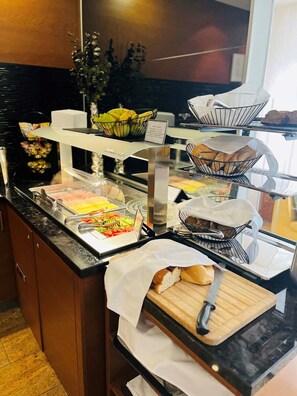 A buffet counter with various food items, including fruits, pastries, and sandwiches. - Mikado Hotel (Nitra)