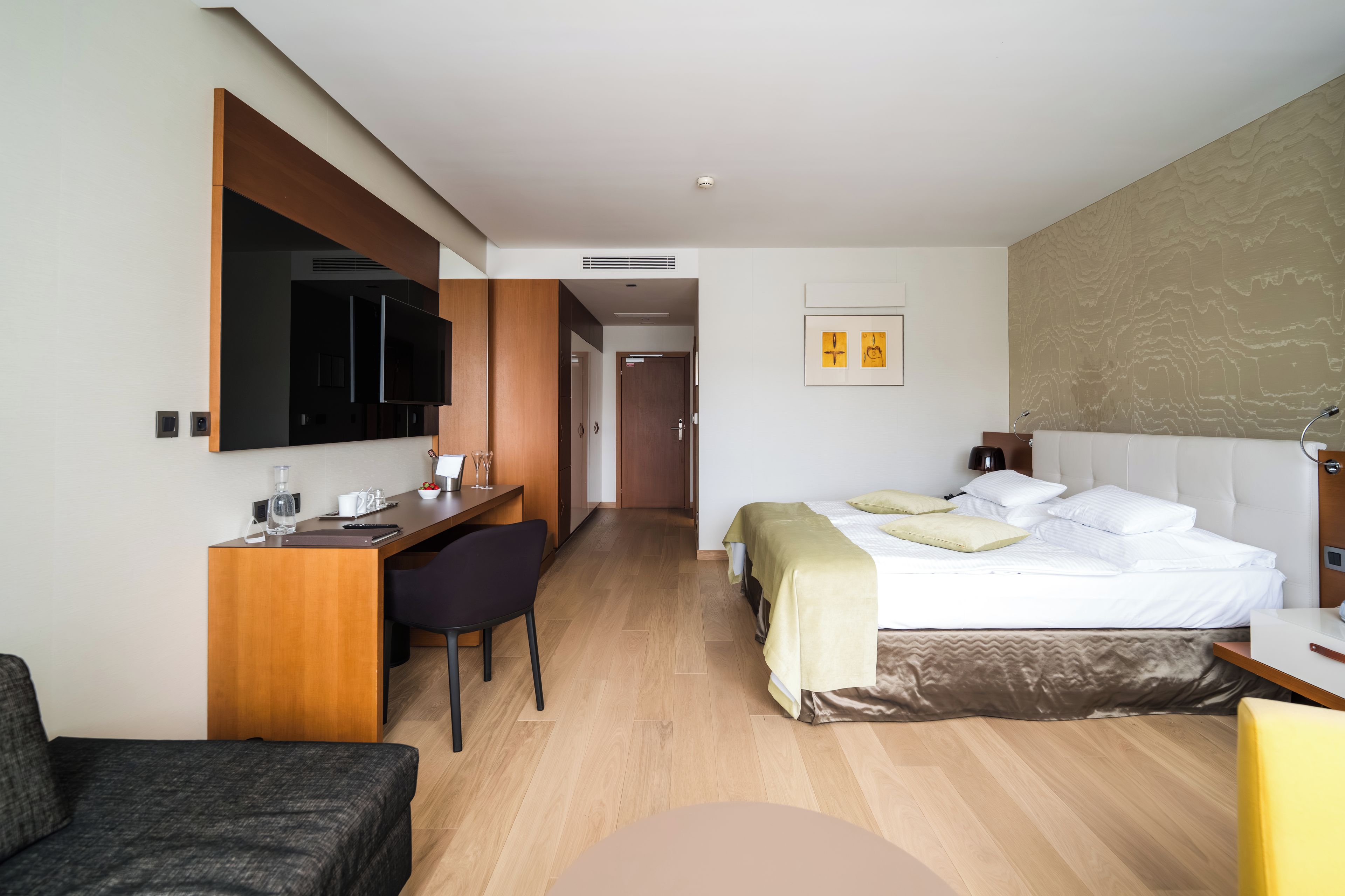 Una camera d'albergo con un letto, una scrivania, una sedia, una televisione e un bagno.