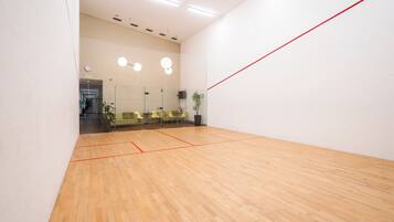 A squash court with wooden flooring and red boundary lines.