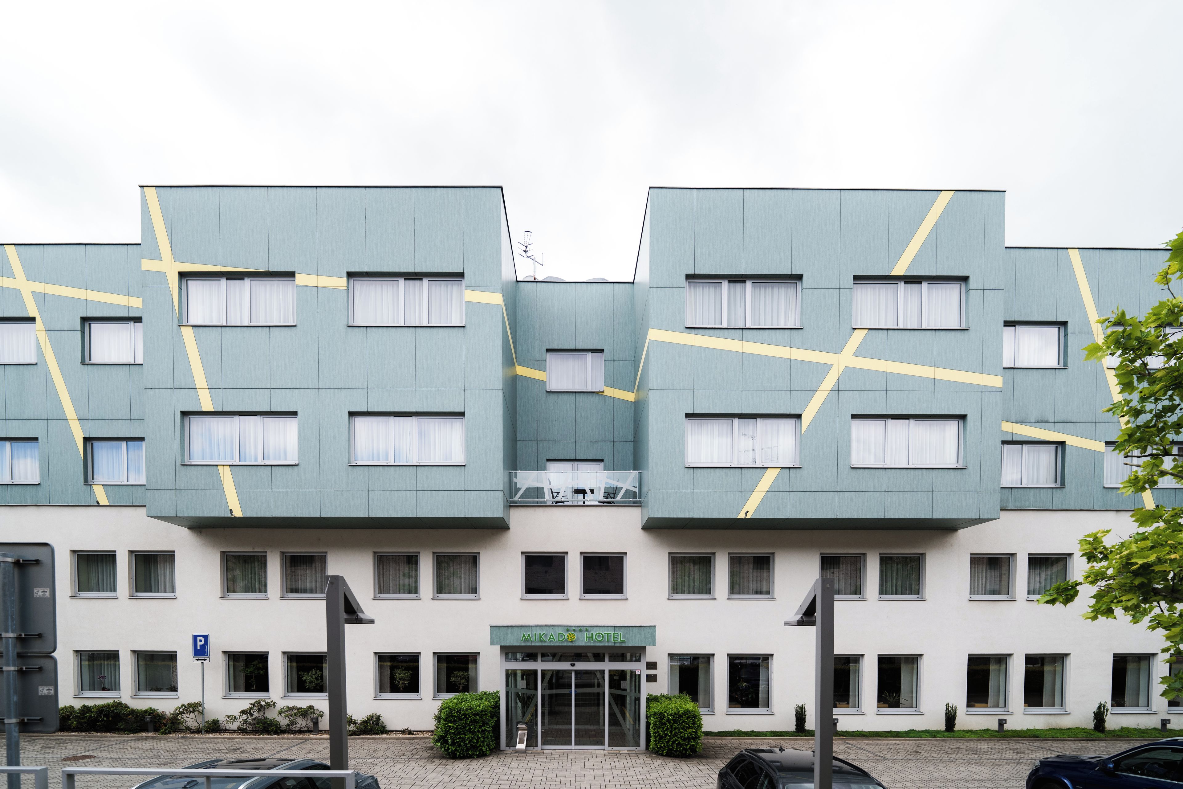 Un hotel moderno con una fachada simétrica, varias ventanas y una entrada central.