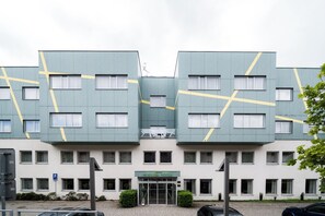 Un hotel moderno con una fachada simétrica, varias ventanas y una entrada central.