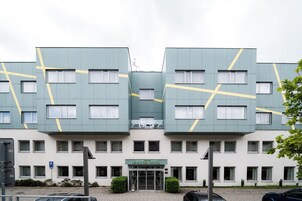 Un hotel moderno con una fachada simétrica, varias ventanas y una entrada central.