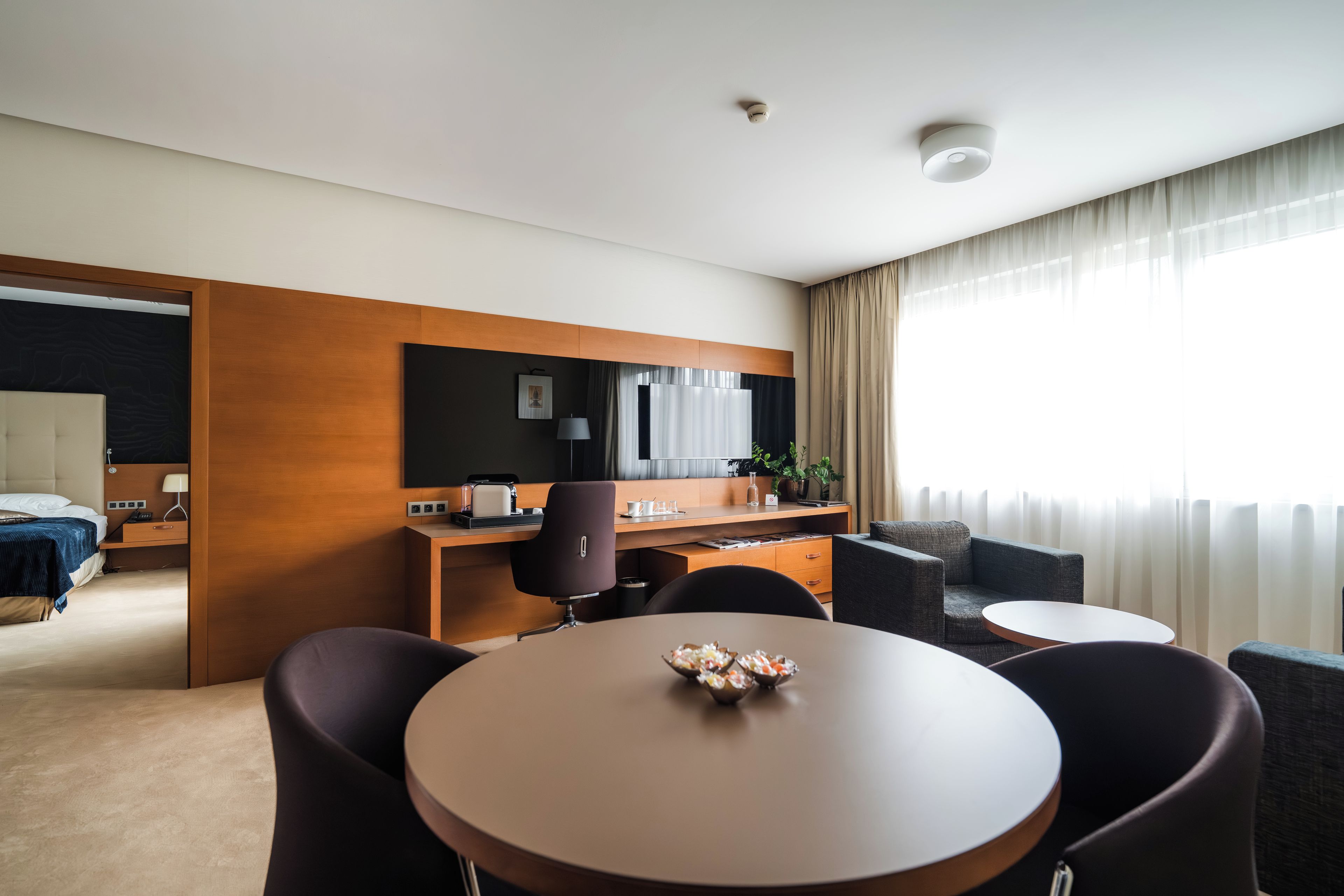 Een hotelkamer met een bed, een bureau, een stoel, een ronde tafel en een bank.