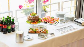 A buffet table with various food items, including a cake, fruits, and pastries, along with bottles of beverages.