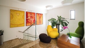 A modern interior with a staircase, artwork, and seating. - Mikado Hotel (Nitra)