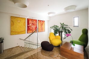 A modern interior with a staircase, artwork, and seating. - Mikado Hotel (Nitra)