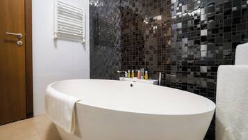 Un baño moderno con una bañera independiente, un perchero para toallas y un dispensador de toallas en la pared.