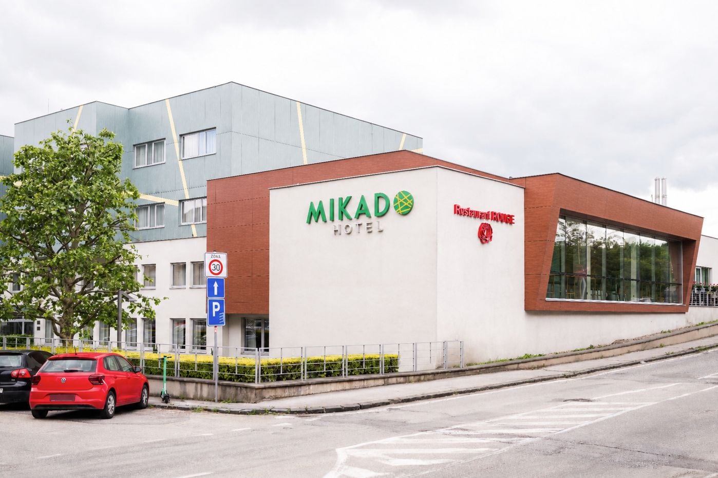 A hotel named MIKADO HOTEL with a modern design, a restaurant named Restaurant House, and a speed limit sign of 30.
