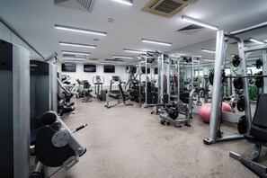 A gym with various exercise equipment, including treadmills, weight machines, and free weights. - Mikado Hotel (Nitra)